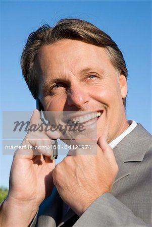 A happy smiling businessman enjoys a friendly chat on his cellphone.