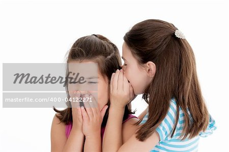 Two Caucasian girls telling secrets on white background