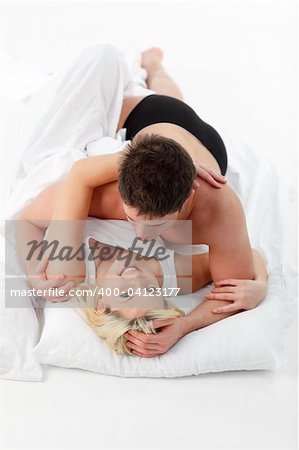 Happy young couple lying together on bed