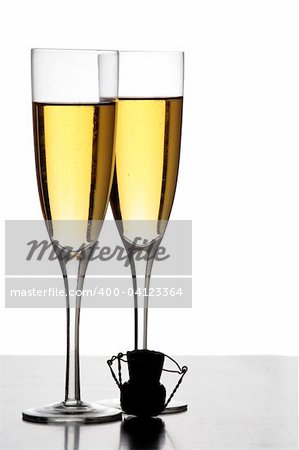 Two champagne glasses and a cork in silhouette