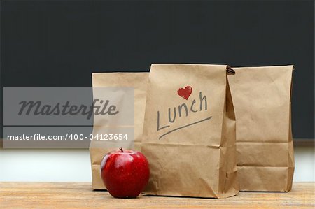 Sacs en papier déjeuner avec pomme rouge sur le banc d'école