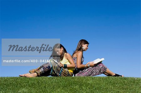 Zwei junge Mädchen lesen isolierten am blauen Himmel