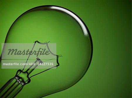Close up on a transparent light bulb over a green background.