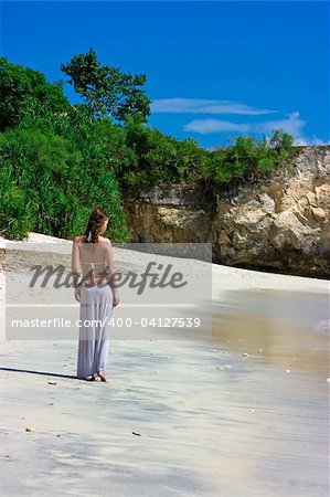 Beautiful brunette with long hair walking along the sandy beach on Bali