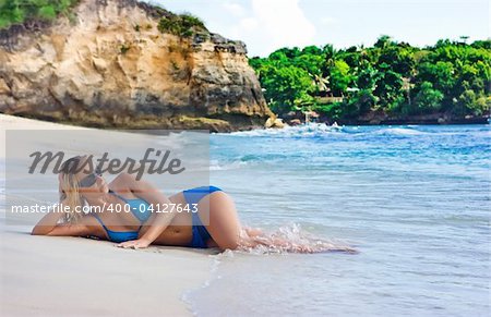 Blonde girl lying on the beach of Bali island