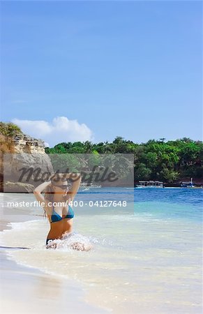 Jeune fille blonde assise sur le sable blanc sur la plage