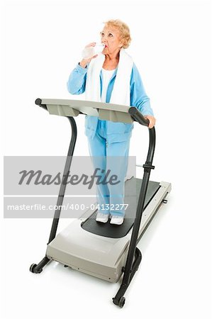 Fit senior woman working out on a treadmill, taking a break to stay hydrated.
