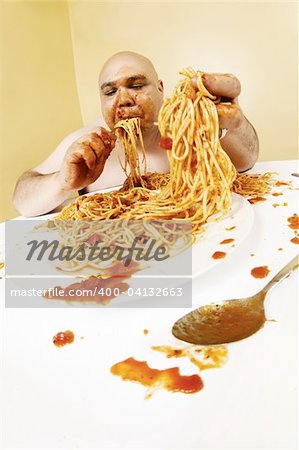 An overweight bald man enjoying a plate of spaghetti.  Shot with fish-eye lens.  Focus is on the face.