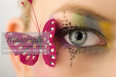 woman eye close up with creative makeup and a butterfly