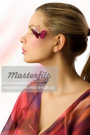 pretty sweet girl in a side view with artistic make up and a butterfly on face
