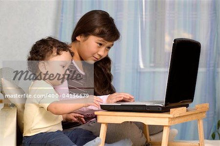 La sœur et le frère junior jouent sur un ordinateur.