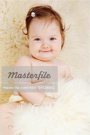 Beautiful baby girl sitting covered with sheepskin