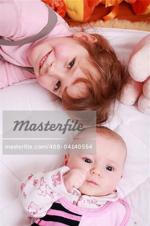 Cute older sister with small baby and toys