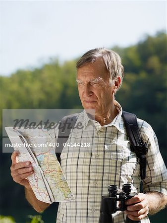 senior hiker holding map and binoculars. Copy space