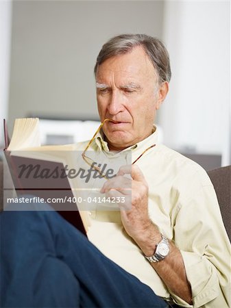 senior man reading book at home