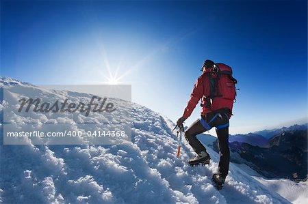 A lone mountaineer reach the top of a high mountain peak. Monte Rosa, Swiss.