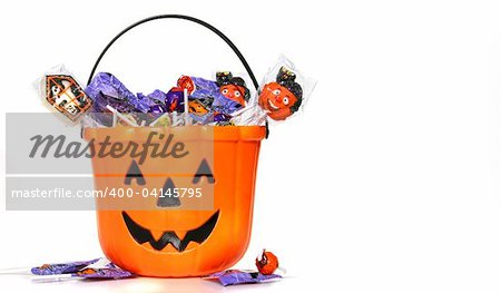 Jack-o-Lantern bucket filled with candies on white background