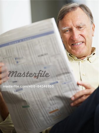 Senior man reading stock listings and smiling