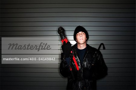 Young burglar in leather jacket with crowbar and bolt cutter