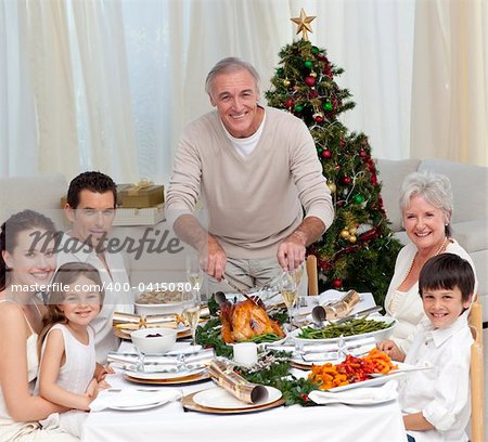 Grandfather cutting turkey for Christmas dinner for his family