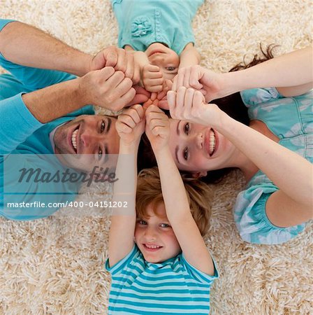 High angle of family lying on floor in a circle with heads and hands together