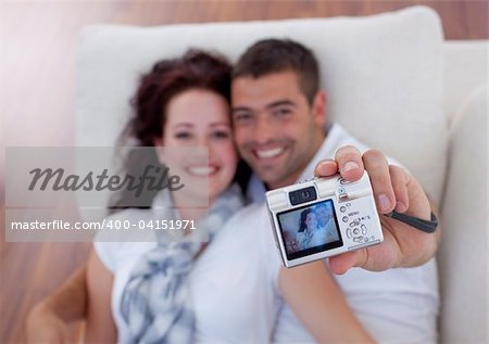 Couple playing with digital camera at home