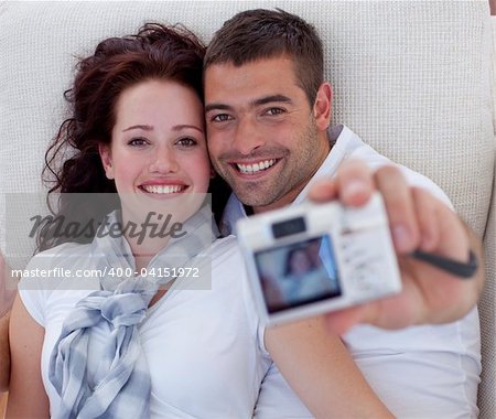 Portrait of couple playing with digital camera at home