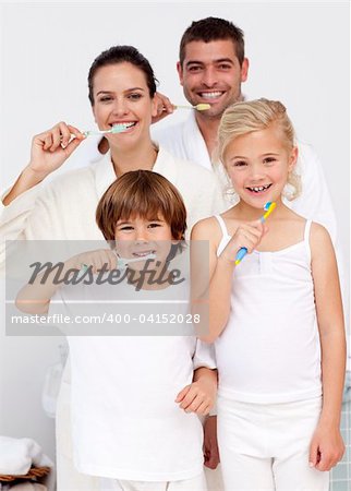 Smiling parents and children cleaning their teeth in bathroom