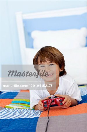 Smiling little boy playing videogames in his bedroom