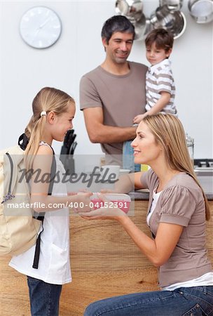 Mother giving her daughter the school lunch in the kitchen