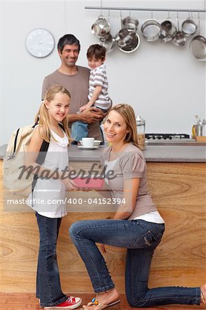 Smiling mother giving daughter the school lunch in the kitchen