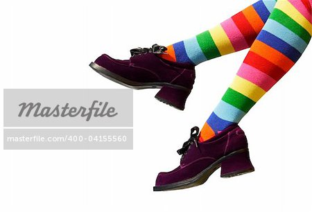 Striped knee-hi socks and wickedly wonky, purple suede shoes on isolated girl's legs.
