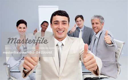 Attractive businessman and his team with thumbs up in the office