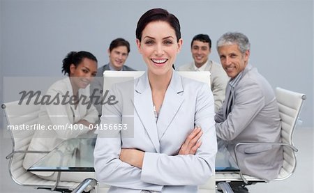 Happy businesswoman smiling in a meeting with her colleagues working in the background