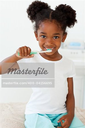 Portrait of a smiling little girl brushing her teeth in the bathroom