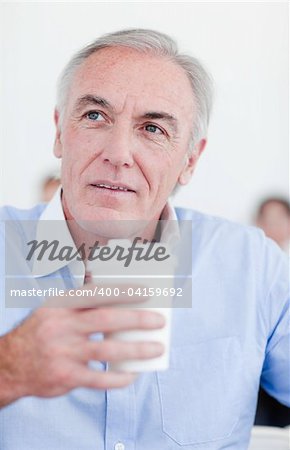 Senior businessman holding a drinking cup at work