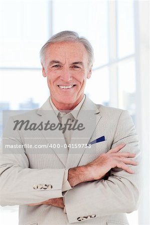 Close-up of a confident senior businessman with folded arms in a business building