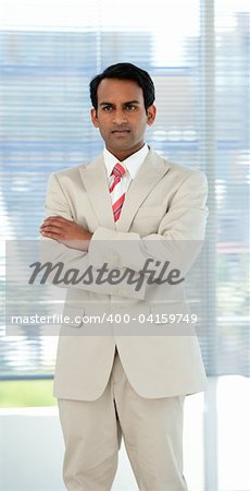 Confident ethnic businessman with folded arms in a business building