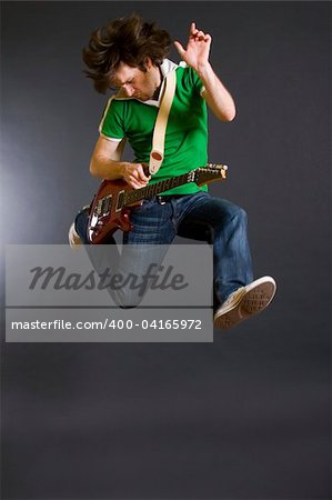 passionate guitarist jumps in the air over dark background