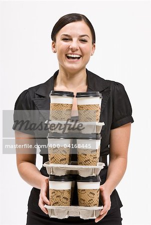 Businesswoman carrying stack of coffee cups