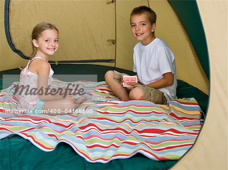 Brother and sister playing cards in tent