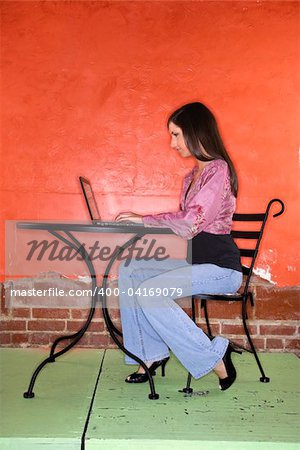 Young woman sitting at a table and using a laptop computer. Vertical shot.