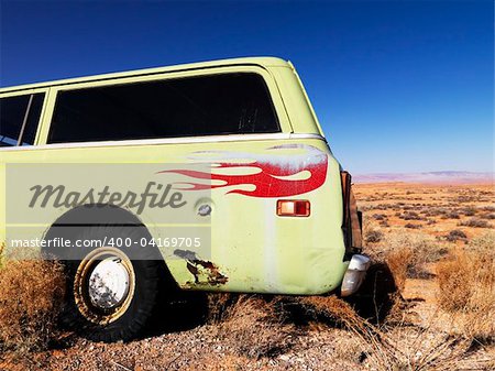 Car with red flames painted on the back parked in the desert. Horizontal shot.