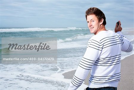 Atractive man on the beach ready to throw a stone into the sea.