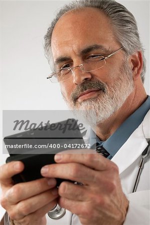 Close-up of a doctor wearing glasses and a lab coat and texting on a cell phone. Vertical shot.