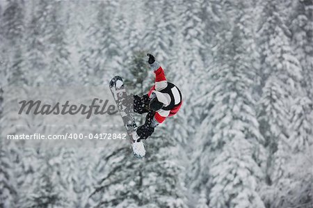 young boys jumping in air ind showing trick with snowboard at winter season