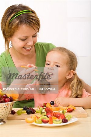 Eating healthy fruits is delicious and fun - woman and little girl enjoying a fresh dessert