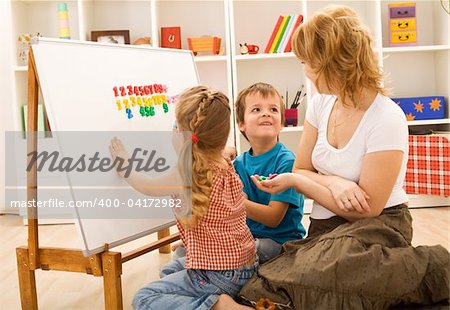 Preschool kids sitting on the floor doing math exercises with their mother