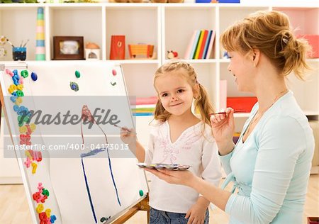 Little girl painting and having fun with her mother at home