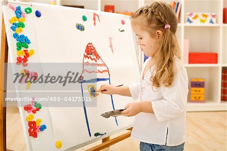 Little girl painting a colorful house on a large paper